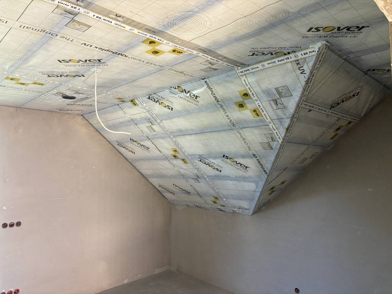 Izolacja poddasza z folią paroizolacyjną Isover Vario KM Duplex UV, widoczne kable elektryczne. Ściany przygotowane do dalszych prac wykończeniowych.
