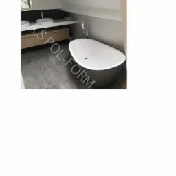 Nowoczesna łazienka na poddaszu z wolnostojącą, szarą wanną, dwiema umywalkami nablatowymi i szarą, geometryczną ścianą.