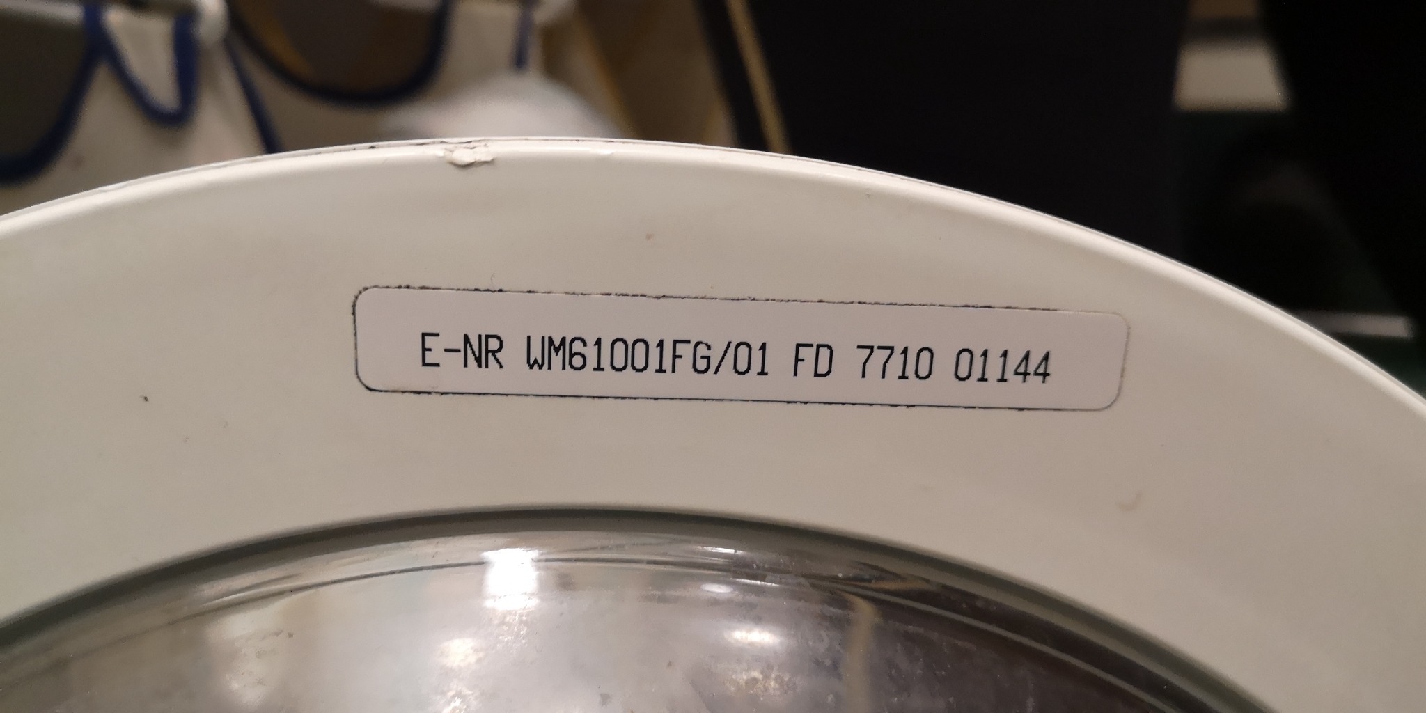 Etykieta z numerem modelu zmywarki E-NR WM61001FG/01 FD 7710 01144 na białej obudowie urządzenia.