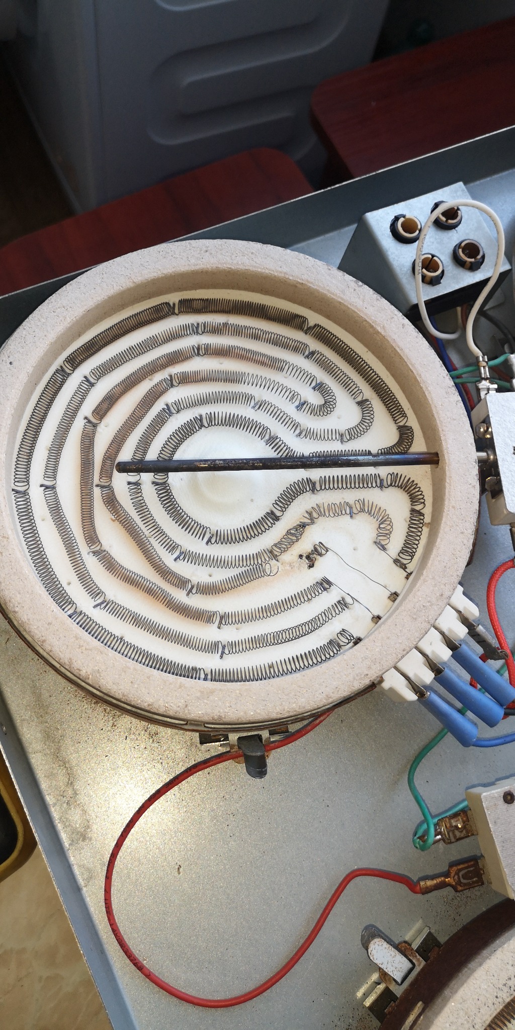 Grzałka spiralna z elementem grzejnym w zmywarce, widoczne przewody i złącza elektryczne.