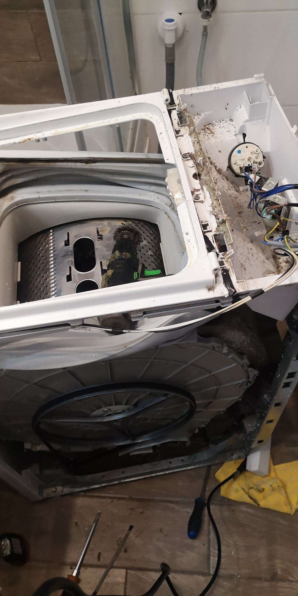 Rozłożona zmywarka w trakcie naprawy w Krakowie, widoczne wnętrze bębna, elementy obudowy, narzędzia i zabrudzenia.