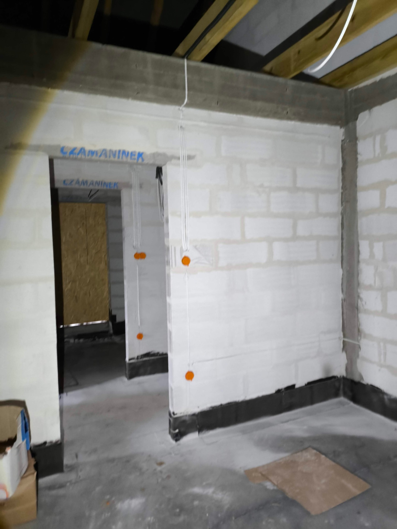 Surowy stan budynku w Gąsocinie po rozprowadzeniu przewodów elektrycznych, widoczne puszki instalacyjne na ścianach z betonu komórkowego.