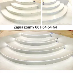 Półokrągłe, białe schody z podświetleniem LED na każdym stopniu, wykonane z gładkiego materiału, z widoczną taśmą maskującą zabezpieczającą krawędzie podczas montażu.