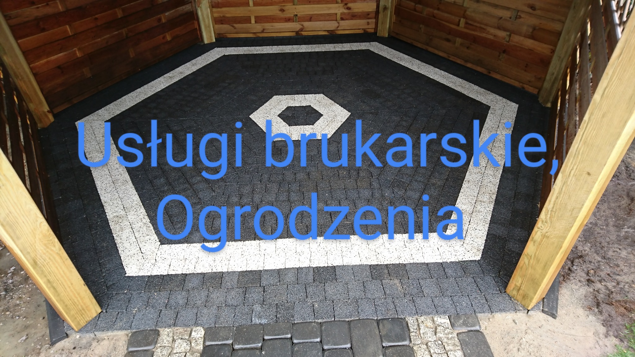 Wykończona podłoga altany z ciemnej kostki brukowej z jasnymi akcentami w kształcie wielokąta, widoczne drewniane słupy konstrukcyjne.