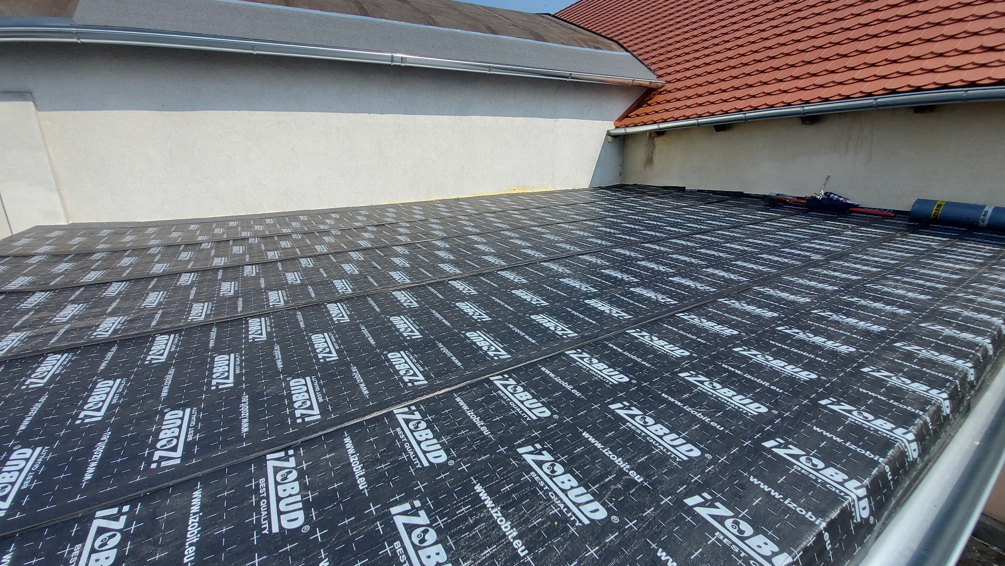 Nowy dach pokryty czarną membraną hydroizolacyjną z widocznym logo producenta, przygotowany pod dalsze prace dekarskie.