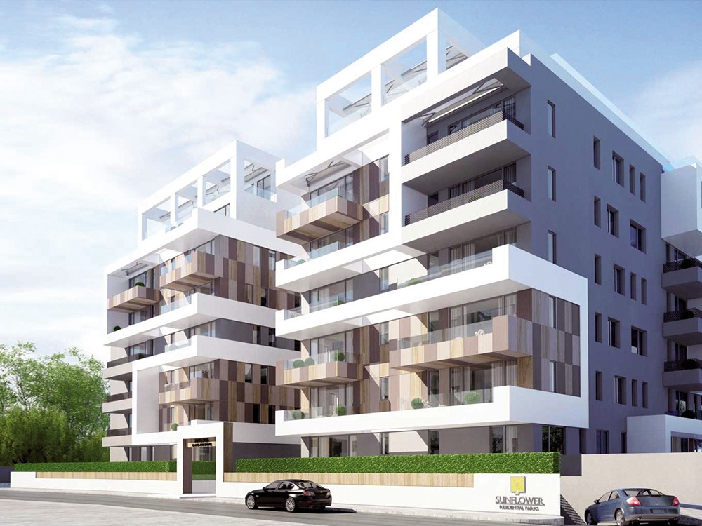 Wizualizacja nowoczesnego apartamentowca z balkonami o drewnianej okładzinie, białą elewacją i szarymi ścianami bocznymi, otoczonego niskim żywopłotem i dwoma zaparkowanymi samochodami.