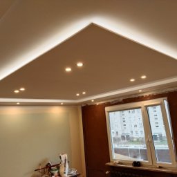 Łukasz USŁUGI BUDOWLANE - Wykończony sufit podwieszany z oświetleniem punktowym i listwami LED w Borowie, widoczne przygotowania do dalszych prac wykończeniowych na ścianach.