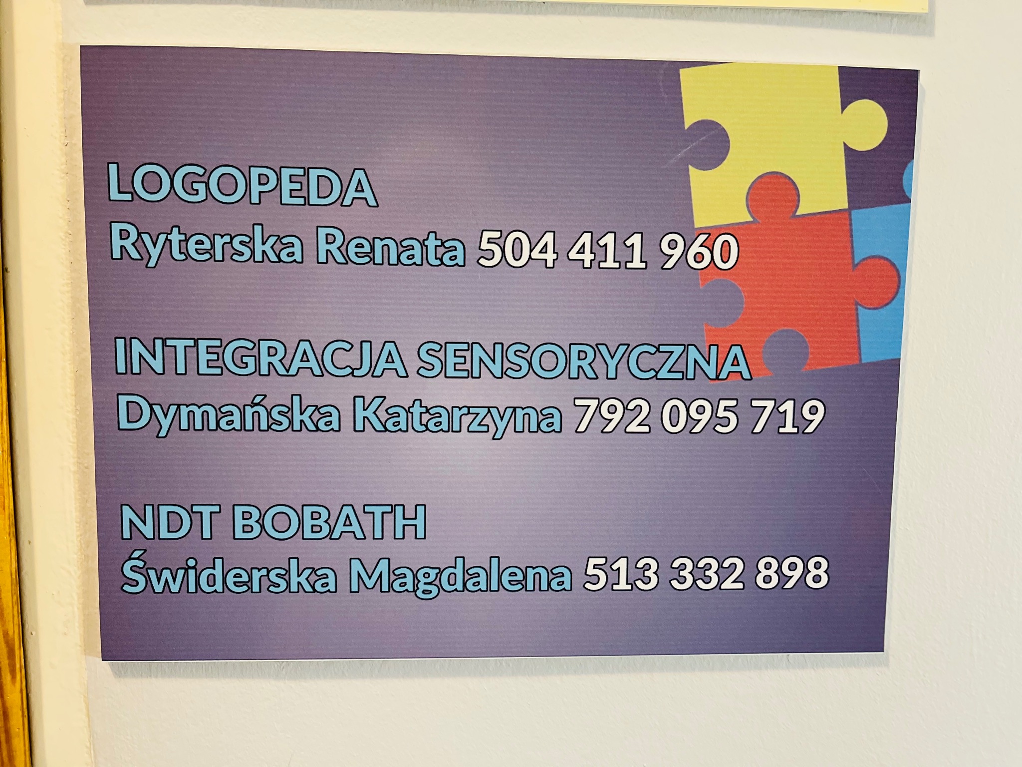 Tablica informacyjna z danymi kontaktowymi do logopedy Ryterskiej Renaty, specjalisty od integracji sensorycznej Dymańskiej Katarzyny i terapeutki NDT Bobath Świderskiej Magdaleny, ozdobiona...
