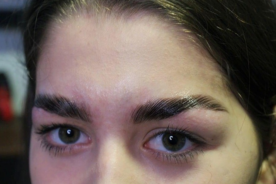 Zbliżenie na twarz kobiety z brwiami po zabiegu laminacji, widoczne błyszczące włoski i naturalny odcień skóry.