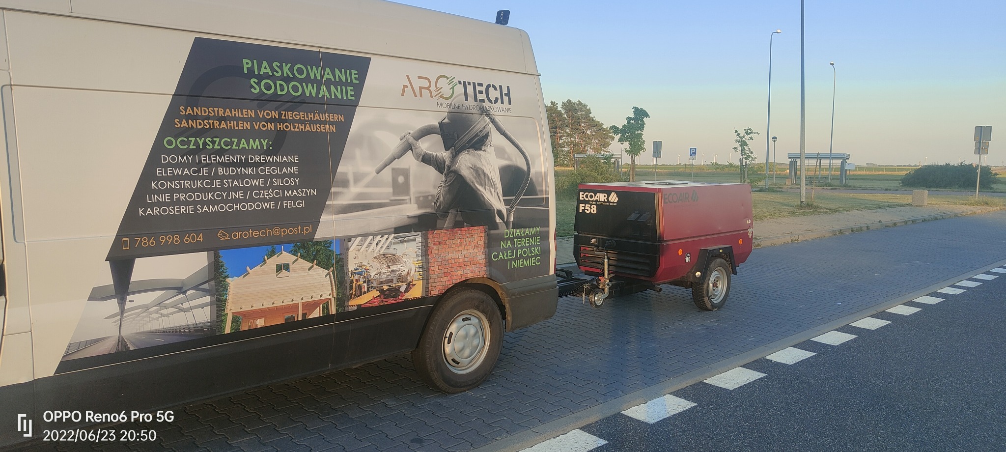 Mobilny kompresor powietrza ECOAIR F58 podpięty do busa z reklamą firmy oferującej usługi czyszczenia strumieniowo-ściernego, w tym elewacji, konstrukcji stalowych i karoserii samochodowych.