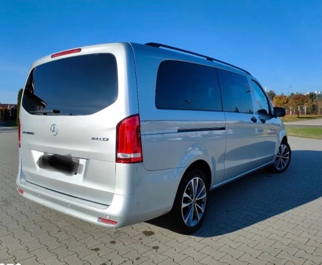 Srebrny Mercedes-Benz Vito 114 CDI z przyciemnianymi szybami, widziany z tyłu na tle kostki brukowej i zieleni.