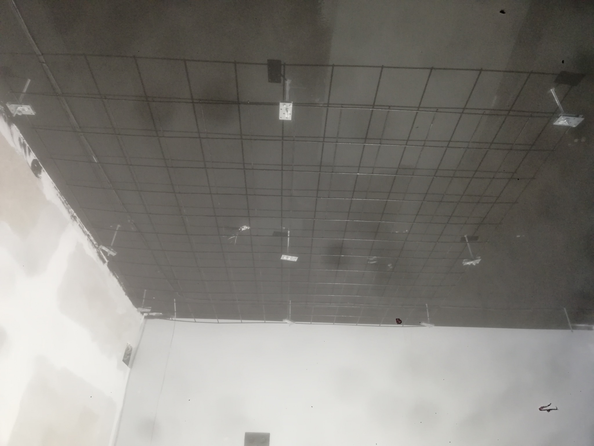 Montaż stelaża pod sufitem napinanym w trakcie prac wykończeniowych w Białystoku. Widoczna metalowa konstrukcja siatkowa przymocowana do sufitu, przygotowana do naciągnięcia membrany.