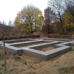Rafal Zaniewicz - Wylane betonowe fundamenty pod budynek jednorodzinny, widoczne zbrojenia, w tle usypana ziemia i jesienne drzewa.