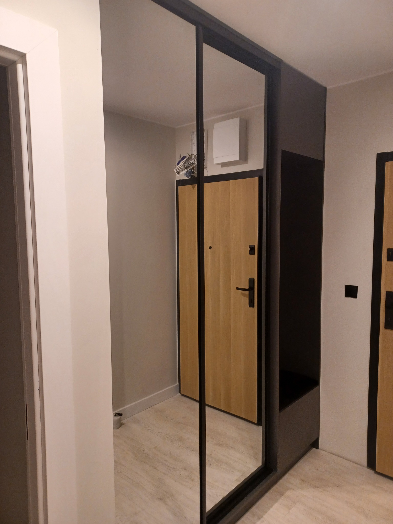 Szafa wnękowa z lustrzanymi drzwiami przesuwnymi i siedziskiem w przedpokoju, odbicie drzwi wejściowych