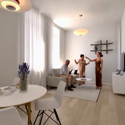 Projektowanie wnętrz Art Centrum Nieruchomości - Jasne wnętrze mieszkania z okrągłym stołem, na którym leżą naleśniki i kawa, oraz z grupą osób w salonie wznoszących toast