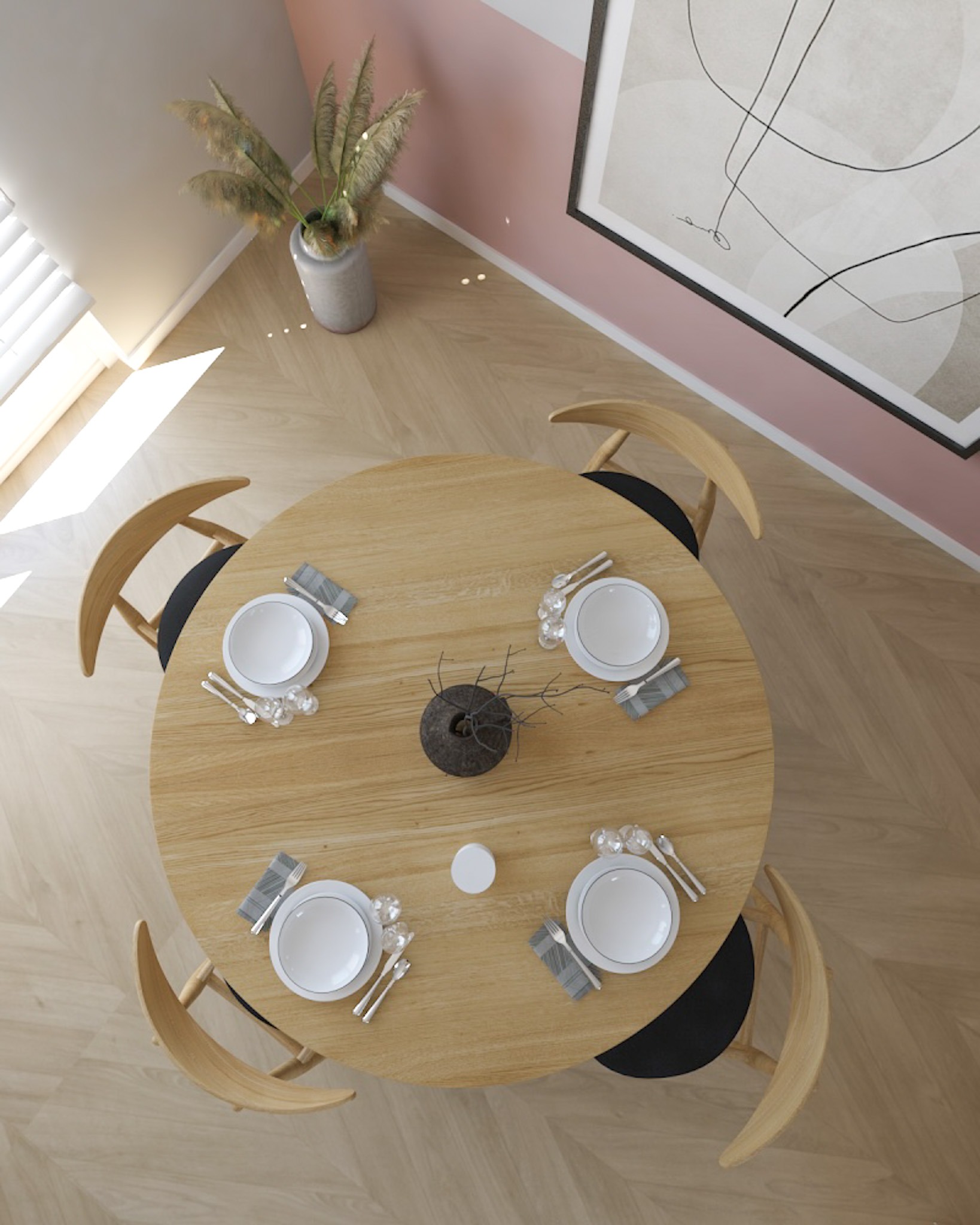 Widok z góry na okrągły, drewniany stół z czterema nakryciami, centralnie umieszczony wazon z suchymi gałązkami, biała świeczka, parkiet w jodełkę, różowo-biała ściana z abstrakcyjnym obrazem.