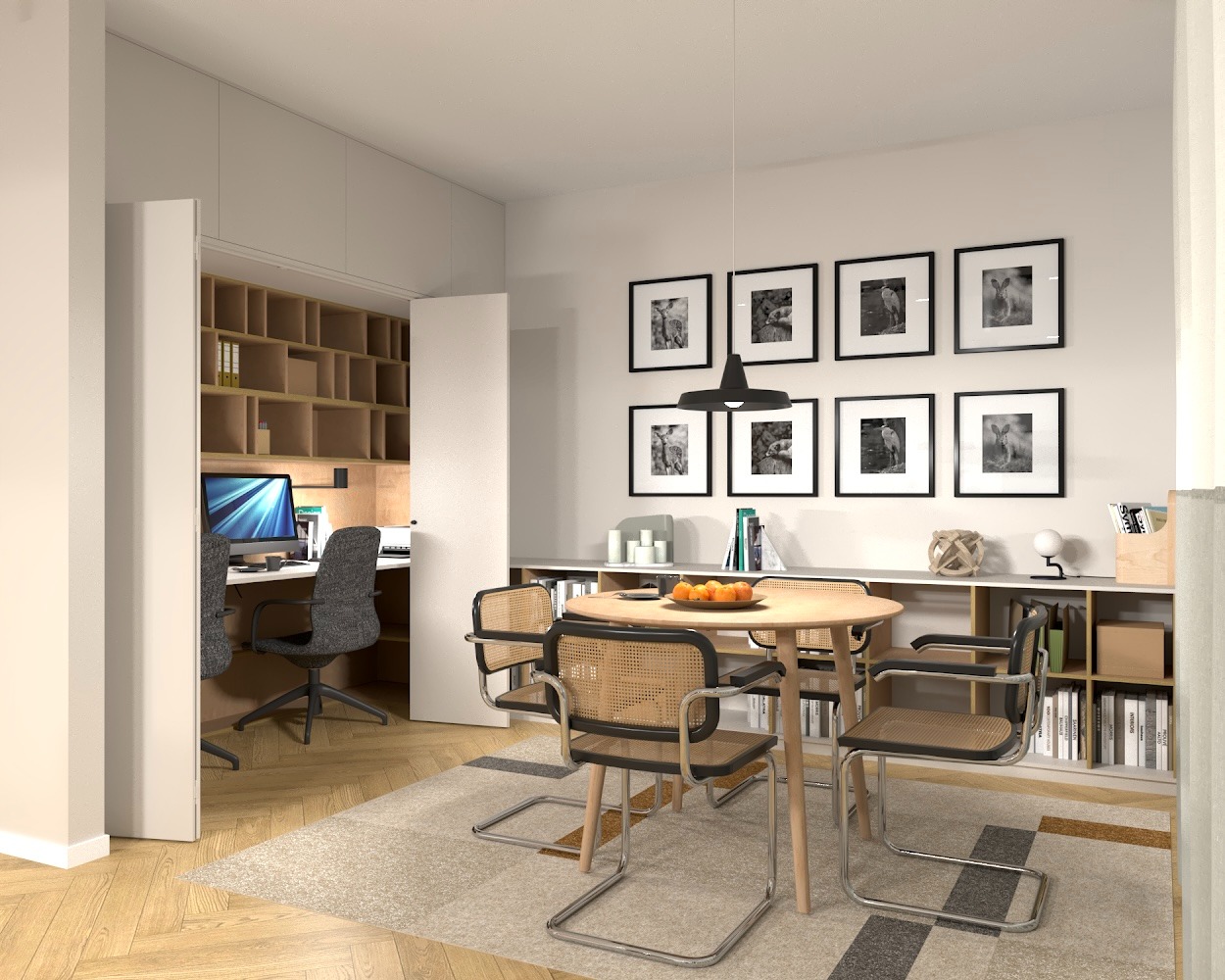 Jasna jadalnia z okrągłym stołem i krzesłami z rattanu, w tle otwarta przestrzeń biurowa z biurkiem i komputerem, ściany zdobi galeria czarno-białych zdjęć.