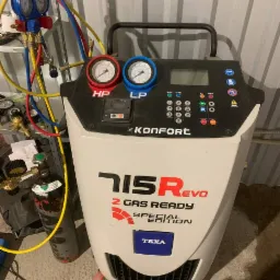 Maszyna TEXA 715R EVO Special Edition do obsługi klimatyzacji samochodowej z podłączonymi przewodami i manometrami, obok butla z gazem chłodniczym.