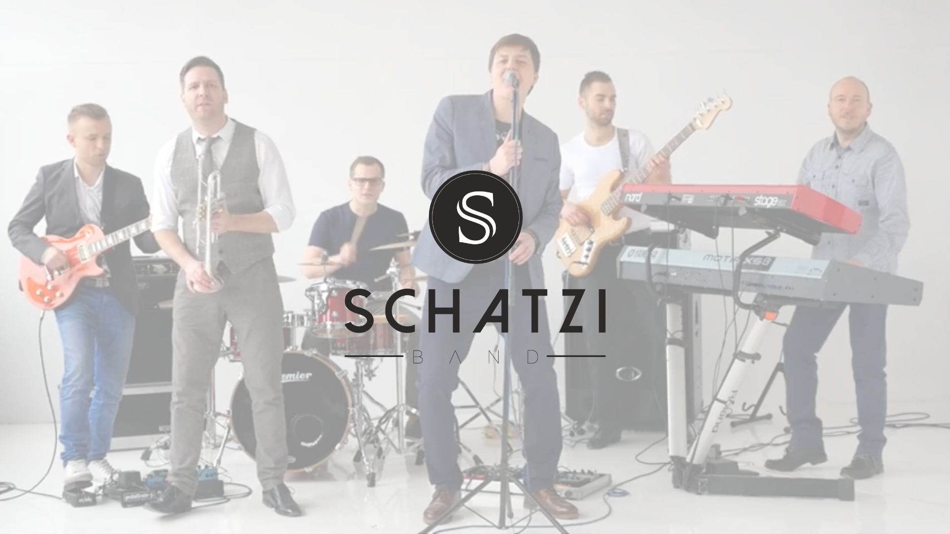 Sześcioosobowy zespół muzyczny w jasnym studiu, wokalista w centrum z mikrofonem, gitarzysta z lewej, trębacz w kamizelce obok, perkusista z tyłu, basista i klawiszowiec z prawej, logo zespołu...