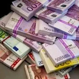 Stosy banknotów euro o różnych nominałach (10, 20, 50, 100, 500) przewiązane banderolami, ułożone chaotycznie na powierzchni.