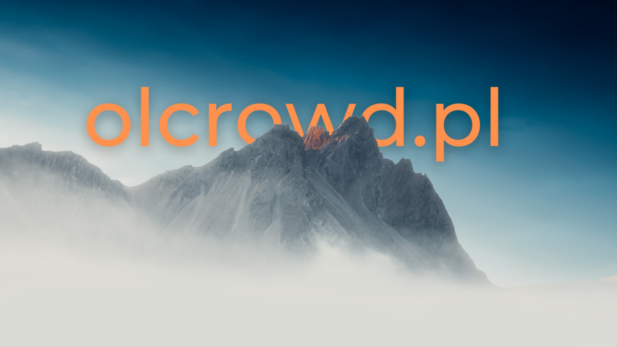 Górzysty krajobraz we mgle z nałożonym pomarańczowym tekstem 'olcrowd.pl'.