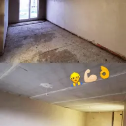 Surowe wnętrze pomieszczenia w stanie deweloperskim po nałożeniu warstwy tynku, widoczne niedoskonałości podłoża i wystające przewody elektryczne.