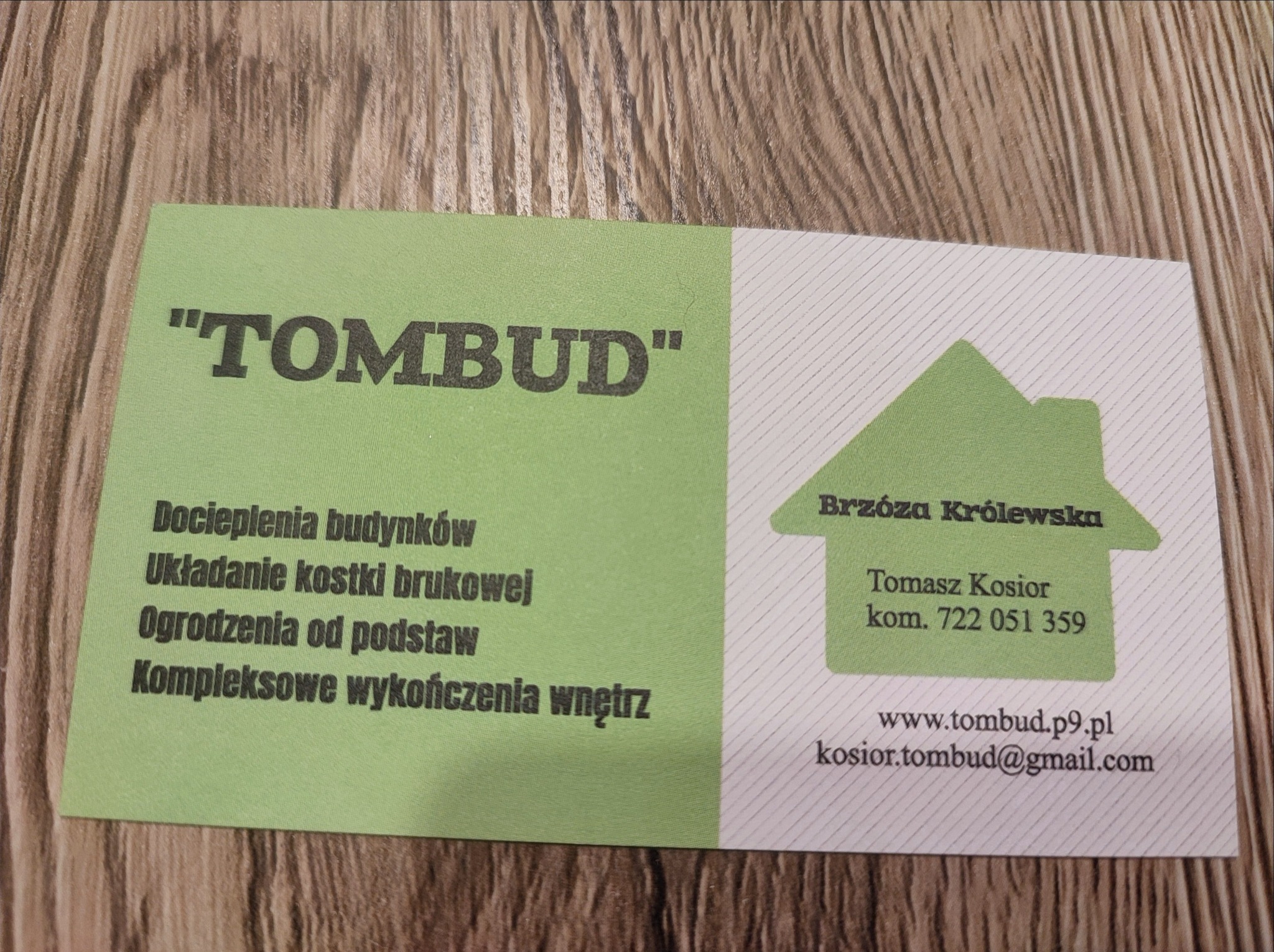 Wizytówka firmy budowlanej TOMBUD z informacjami kontaktowymi i zakresem usług: docieplenia budynków, układanie kostki brukowej, ogrodzenia od podstaw, kompleksowe wykończenia wnętrz, na tle...