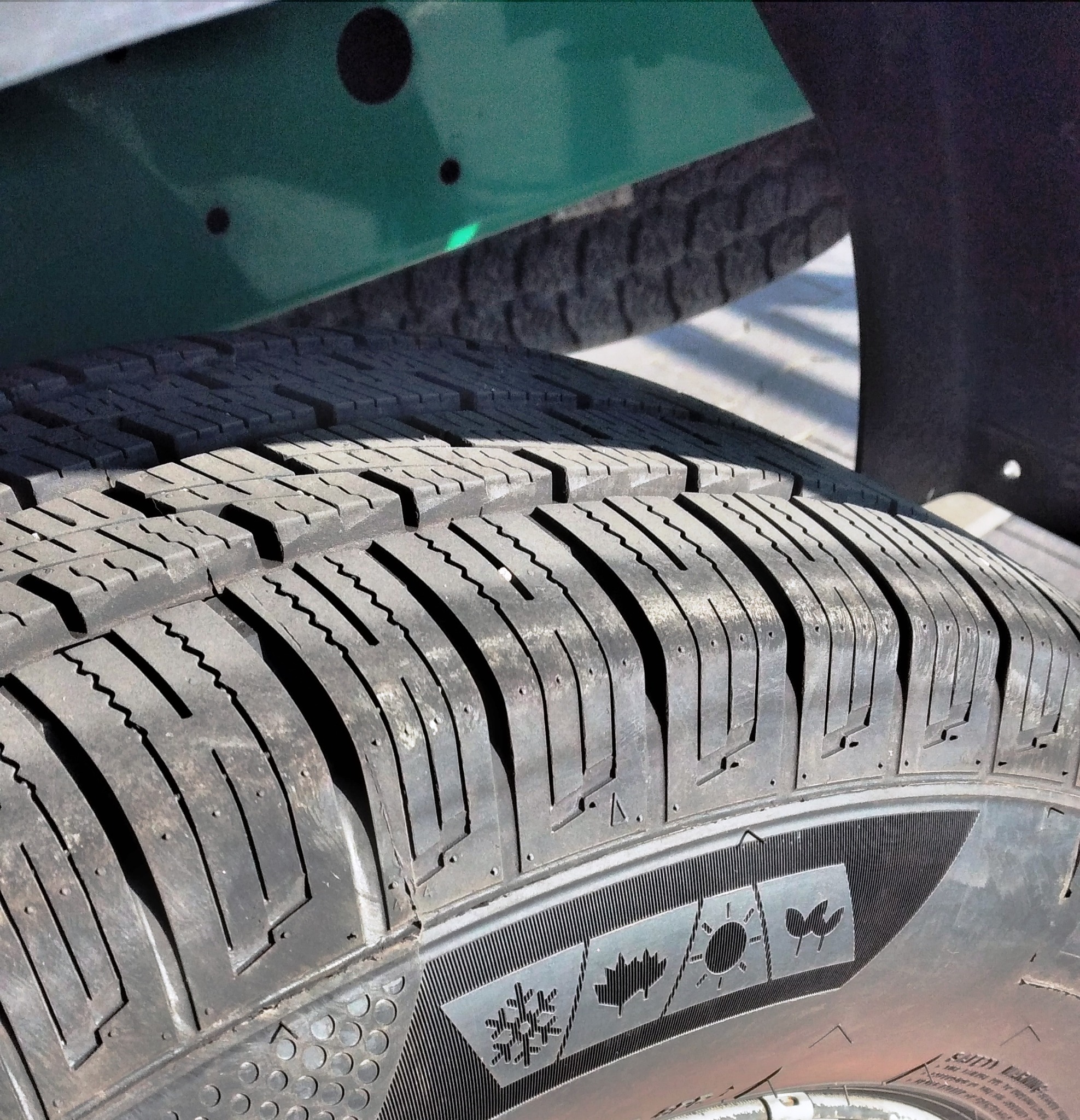 Szczegół opony busa z widocznym bieżnikiem i oznaczeniami: płatek śniegu, liść klonu, słońce, ptak.