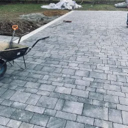 Ułożona szara kostka brukowa na posesji w Jawiszowicach, widoczny wózek z narzędziami i przygotowany teren pod dalsze prace.