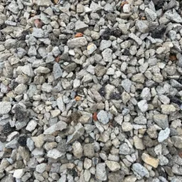 Stos szarego pokruszonego betonu i cegieł z niewielkimi fragmentami asfaltu.