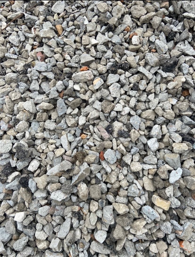 Stos szarego pokruszonego betonu i cegieł z niewielkimi fragmentami asfaltu.