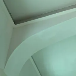 Łukowe przejście w ścianie z surową, częściowo wyszpachlowaną powierzchnią, widoczne mocowania płyty kartonowo-gipsowej na suficie.