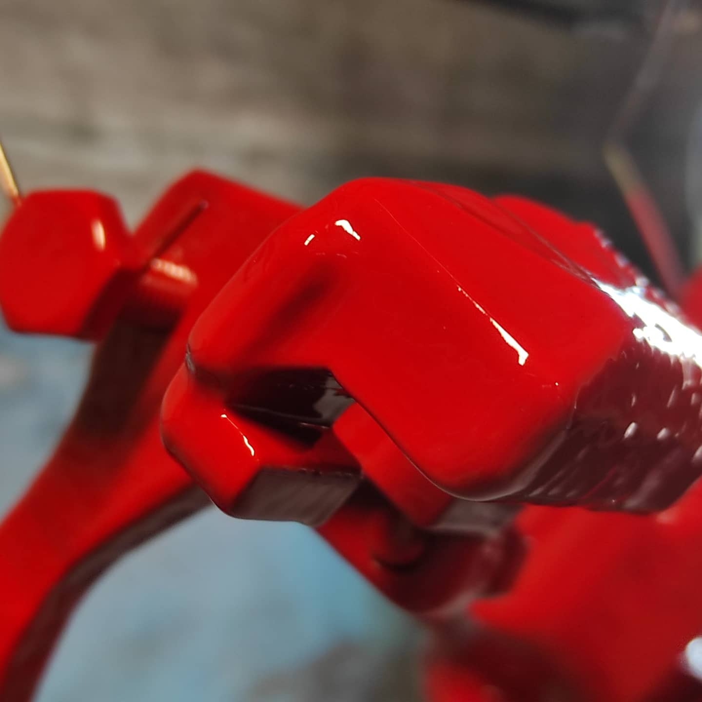 Błyszczące, czerwone elementy metalowe po nałożeniu farby, widoczne refleksy światła.