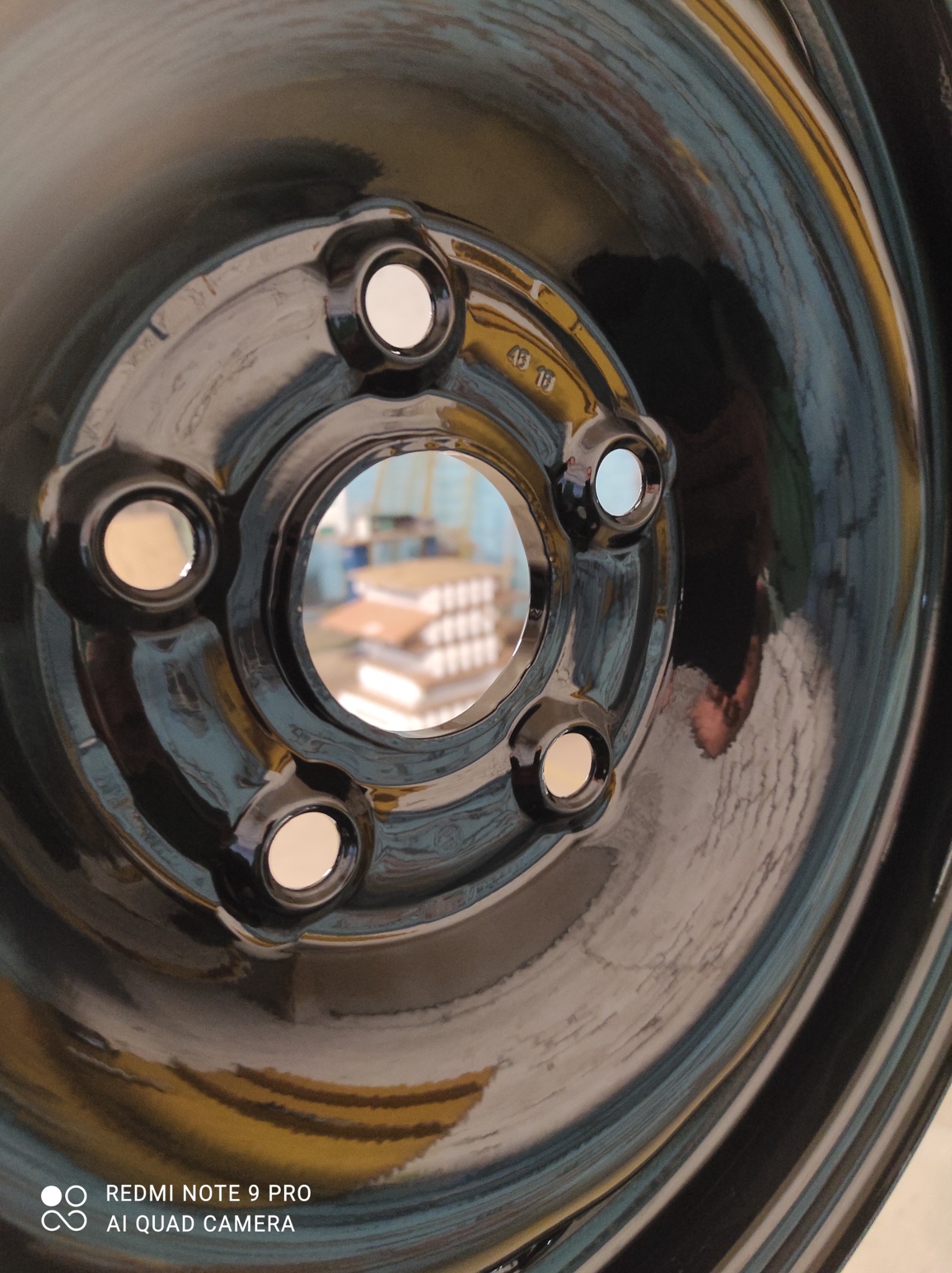 Błyszcząca, czarna felga stalowa po obróbce w Bartoszycach, widoczne otwory montażowe oraz refleksy światła na gładkiej powierzchni.