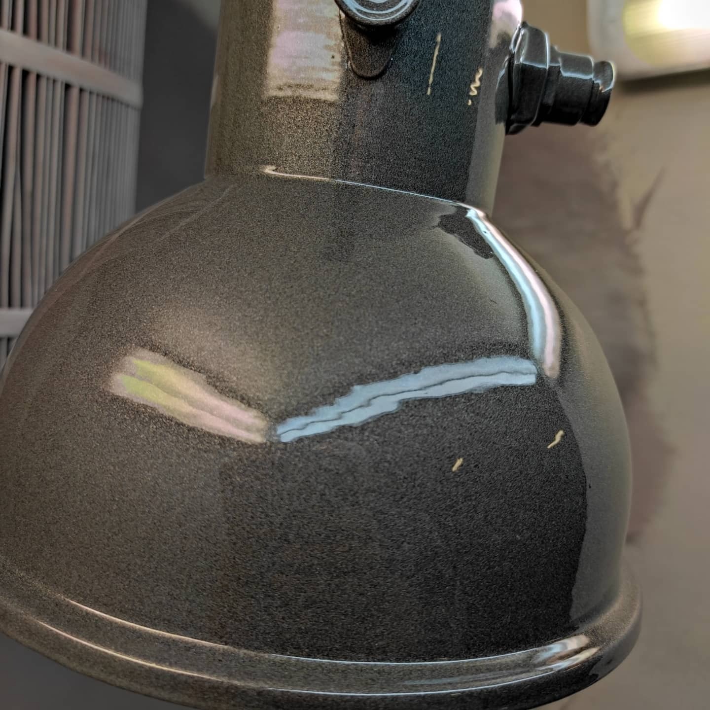 Metalowa lampa przemysłowa po nałożeniu szarej, metalicznej powłoki, widoczne drobne niedoskonałości i odbicia światła.