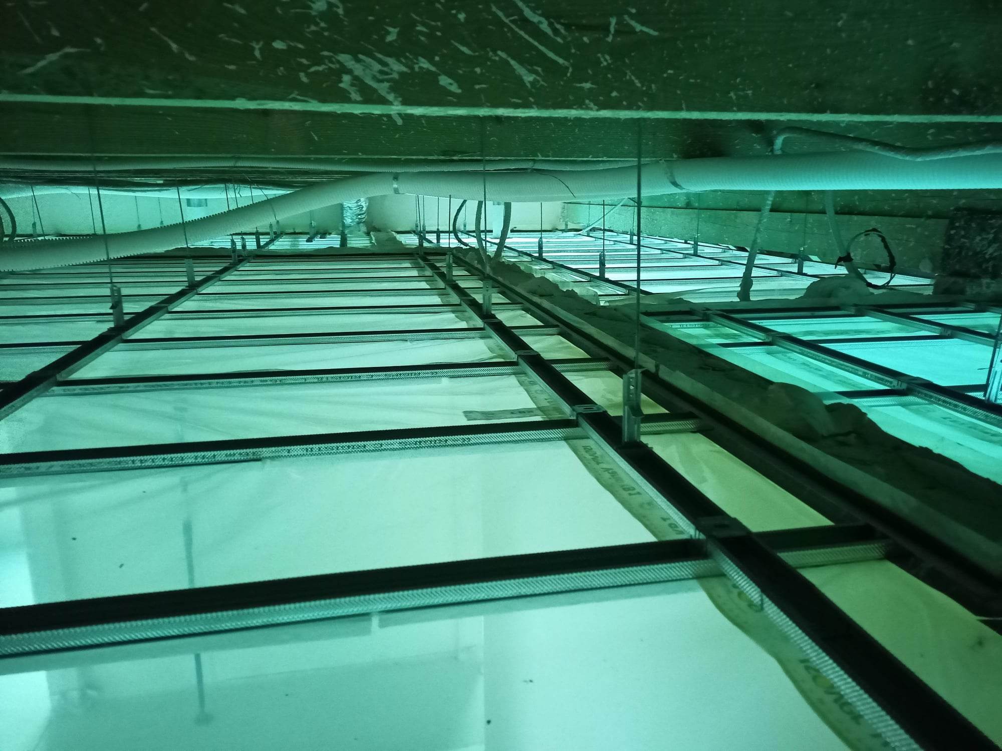 Stelaż metalowy pod sufitem z widoczną instalacją wentylacyjną i ociepleniem, przygotowany do montażu płyt.