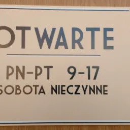 Tabliczka informacyjna z godzinami otwarcia: Otwarte PN-PT 9-17, Sobota Nieczynne, umieszczona na drewnianym tle.