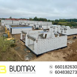 Budmax - Budowa osiedla domów z bloczków betonu komórkowego w trakcie realizacji. Widoczna koparka i fundamenty kolejnych budynków. Całość na tle pochmurnego nieba.