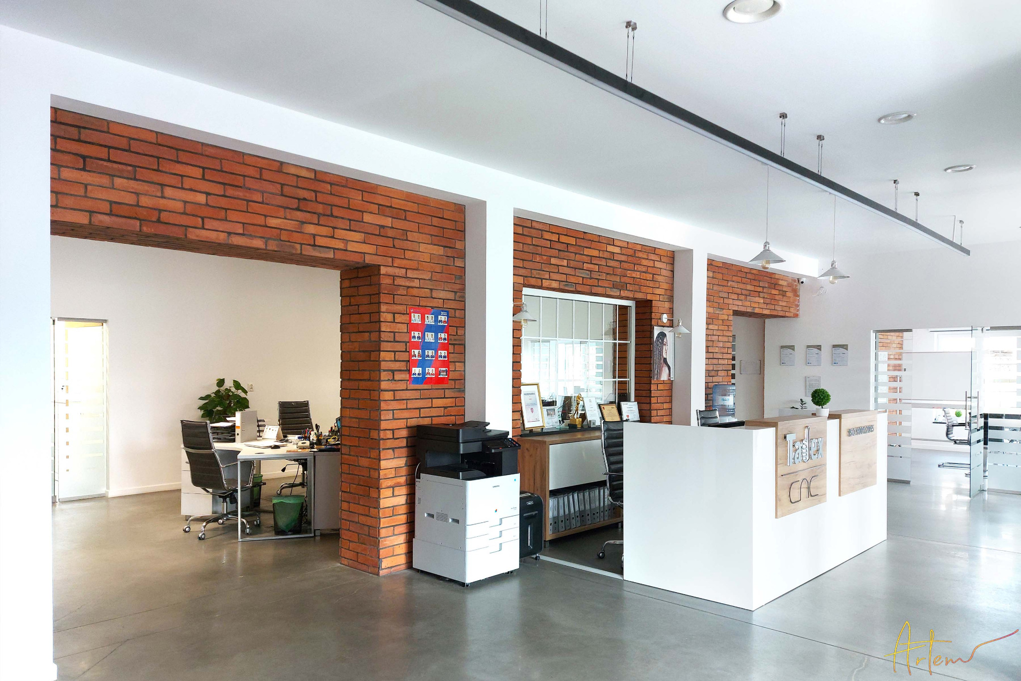 Nowoczesne biuro z recepcją, ściany z cegły, minimalistyczne meble biurowe i szklane drzwi.