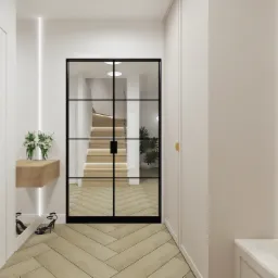 Wnętrze przedpokoju z podłogą w jodełkę, przeszklonymi drzwiami w czarnej ramie, przez które widać schody z podświetleniem LED, oraz drewnianą półką z kwiatami i parą szpilek pod spodem.