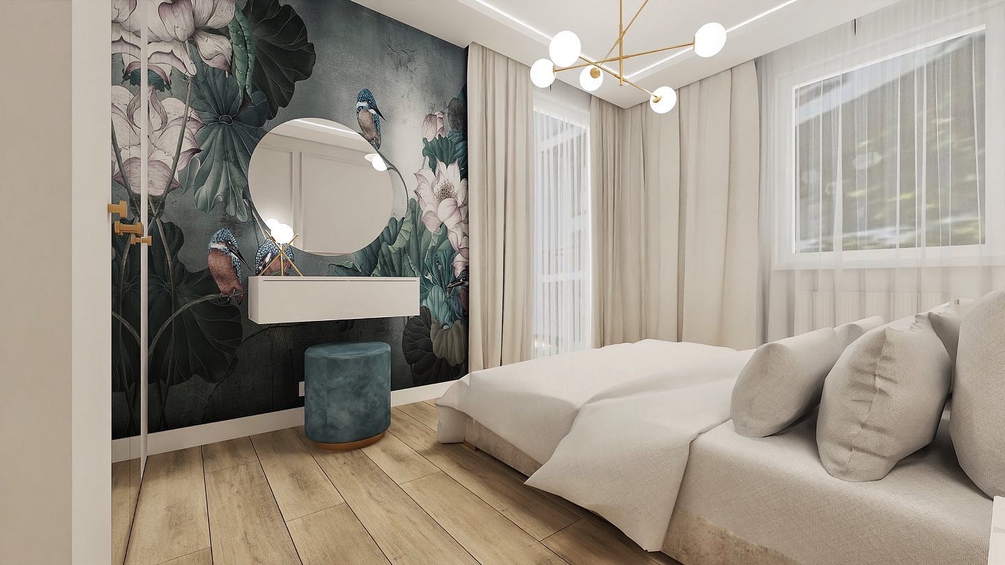 Jasna sypialnia z tapetą w kwiaty i ptaki, okrągłe lustro nad białą konsolą i turkusowy puf, złoty żyrandol z kulistymi kloszami.