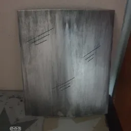 Szara, pionowa płyta z trzema zestawami równoległych, ukośnych nacięć, umieszczona w pomieszczeniu.