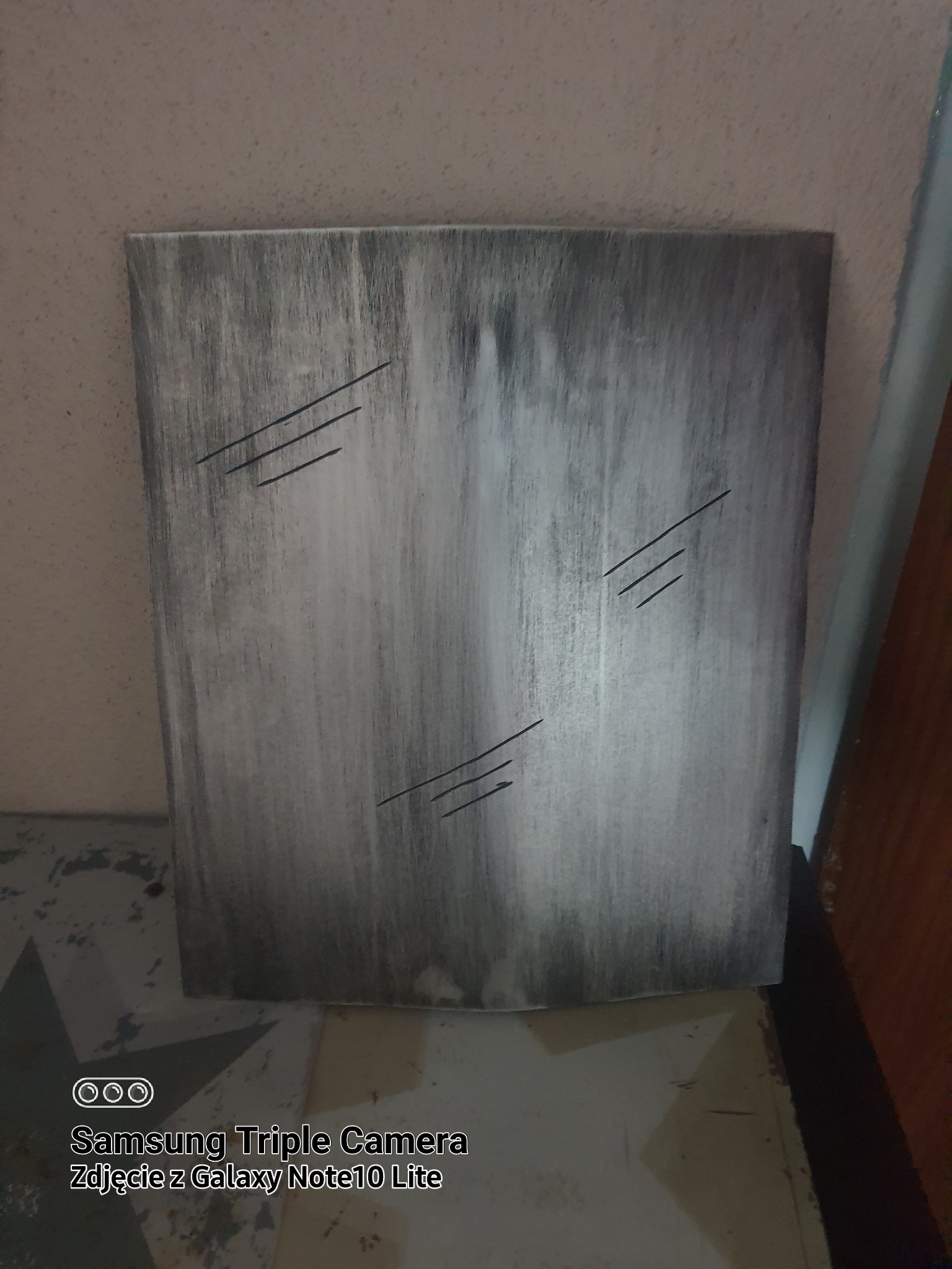 Szara, pionowa płyta z trzema zestawami równoległych, ukośnych nacięć, umieszczona w pomieszczeniu.