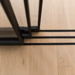 Szczegółowe ujęcie podłogi z jasnego drewna z zamontowanymi czarnymi szynami i elementami konstrukcyjnymi przesuwnych drzwi wewnętrznych.