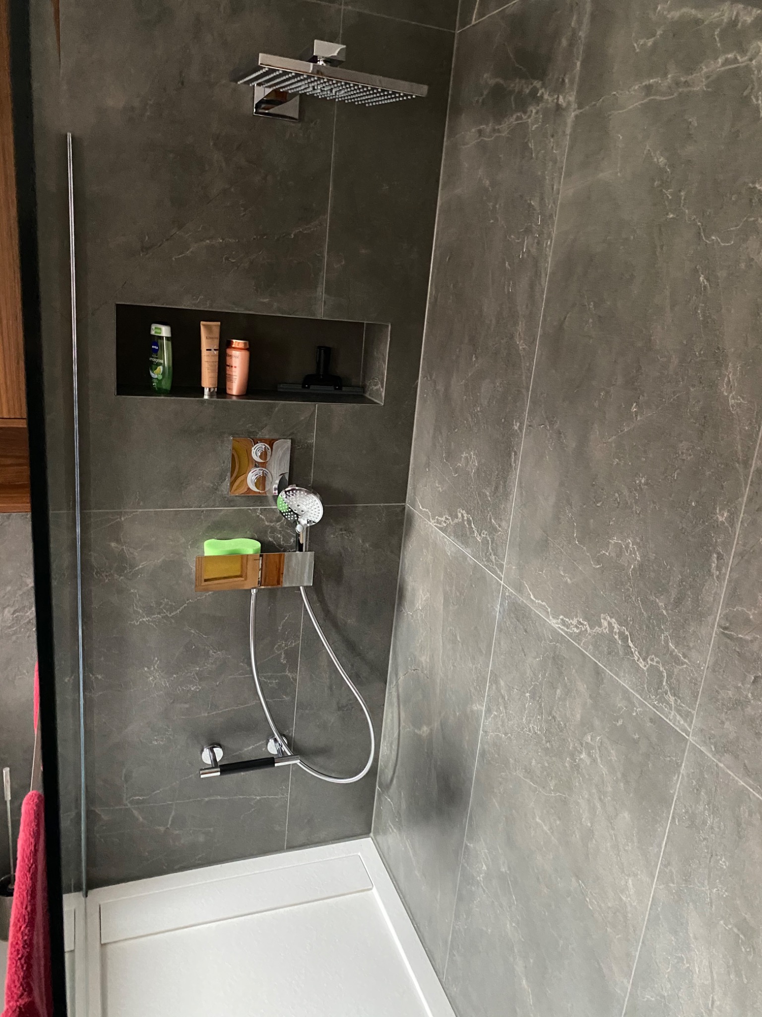 Nowoczesna kabina prysznicowa z deszczownicą i półką wnękową na kosmetyki, wykończona szarymi płytkami imitującymi marmur, zrealizowana w Warszawie.