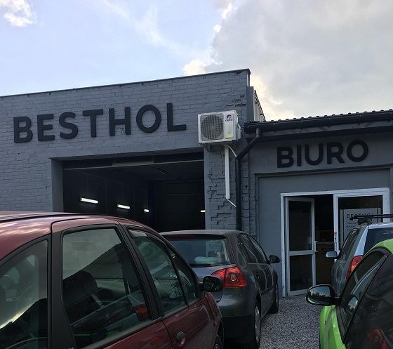 Fasada warsztatu samochodowego Besthol z widocznym wejściem do hali i biura, zaparkowane samochody w pierwszym planie.