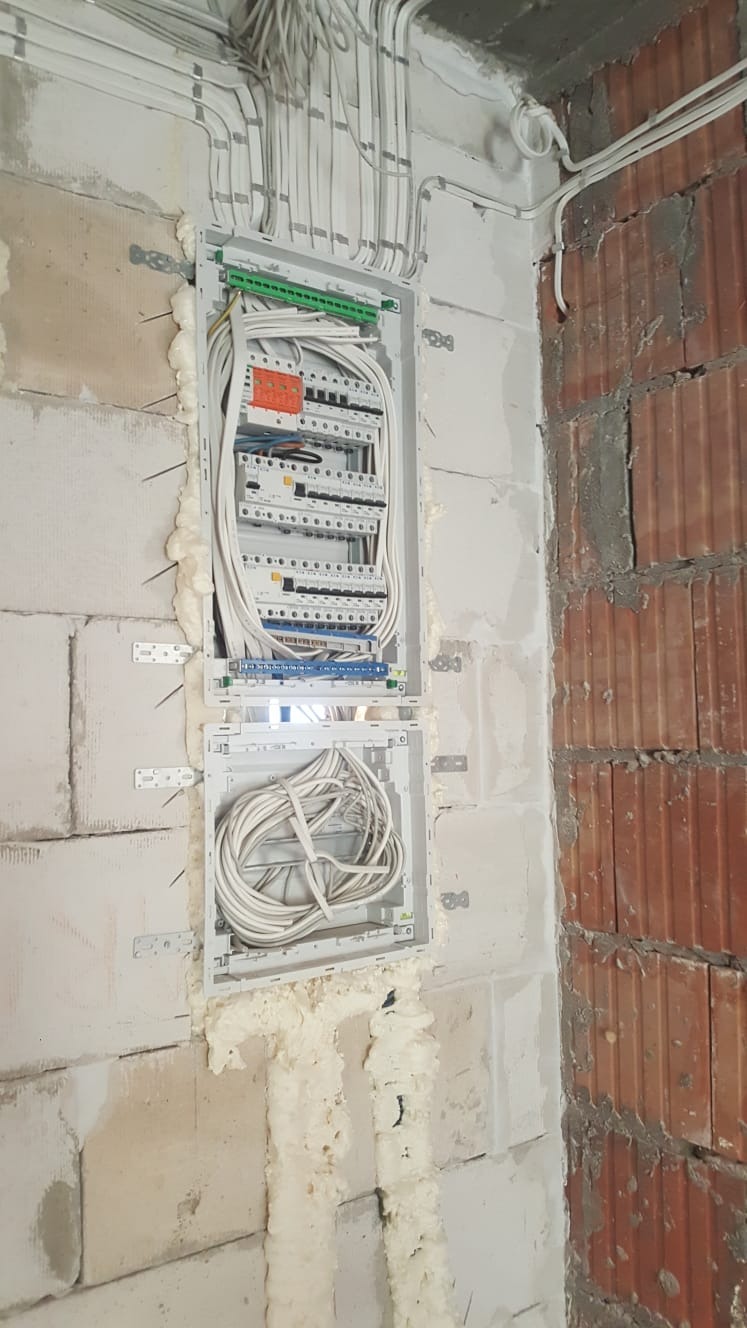 Szafka rozdzielcza z przewodami w ścianie z pustaków, zabezpieczona pianką montażową, widok z Wierzchucina.