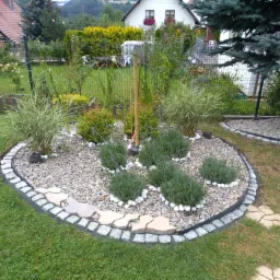 Ogródek skalny z obrzeżem z kostki granitowej i nasadzeniami lawendy, otoczony trawnikiem i zielonym ogrodzeniem siatkowym w Mysłakowicach.