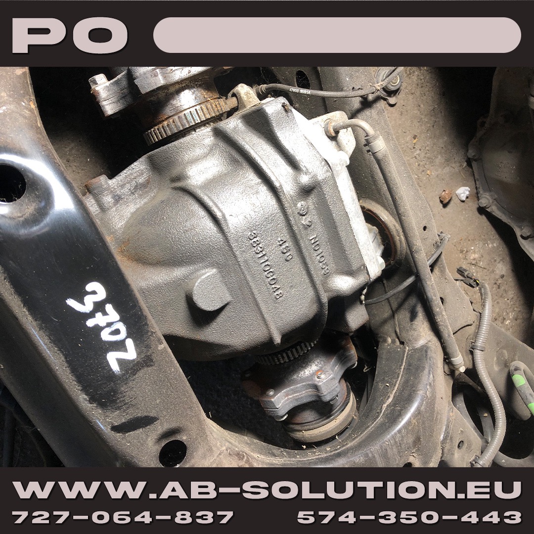 Szary dyferencjał samochodowy zamontowany w ramie podwozia, widoczne numery seryjne i oznaczenia, zarys podwozia i elementy zawieszenia.