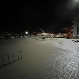 Nocne wylewanie betonu na strop budynku w Klaskach, widoczny dźwig i pracownik w odblaskowej kamizelce.